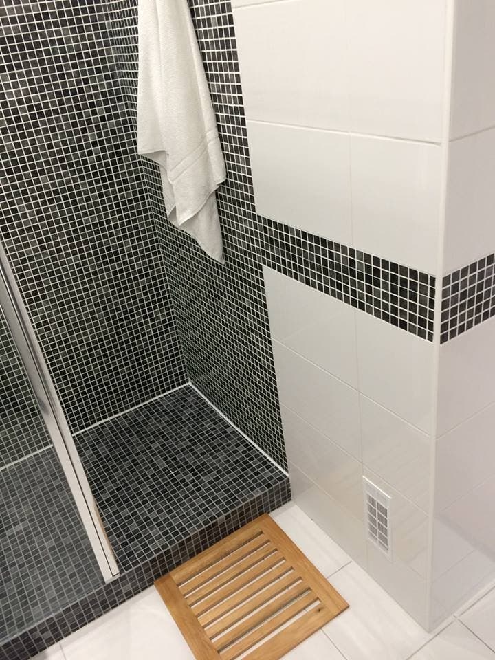 Carrelage uni noir mat petite taille dans une salle de bain avec mur blanc et serviette, sol en bois