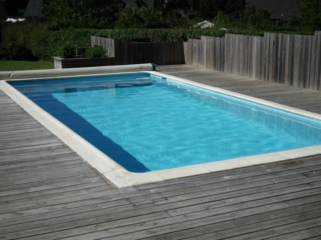 Carreau de ciment bleu clair et foncé sur une terrasse en bois autour dune piscine extérieure aux tons bleu ciel