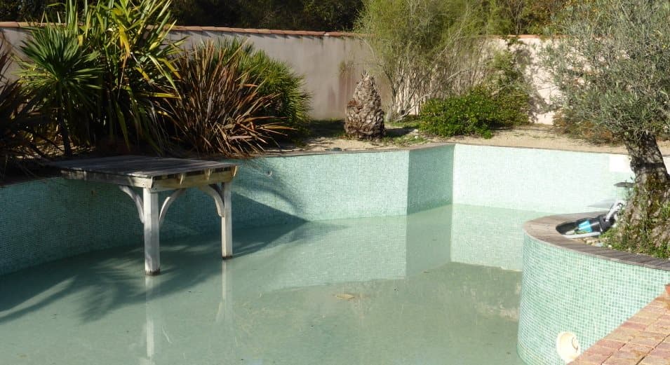 Carrelage uni vert 30x30 cm sur piscine extérieure, entouré de verdure et mobilier de jardin en métal
