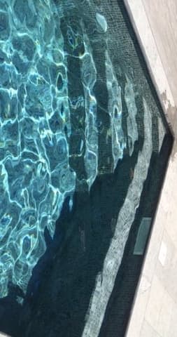 Carrelage gris à texture lisse près dune piscine avec de leau bleu clair et des reflets scintillants