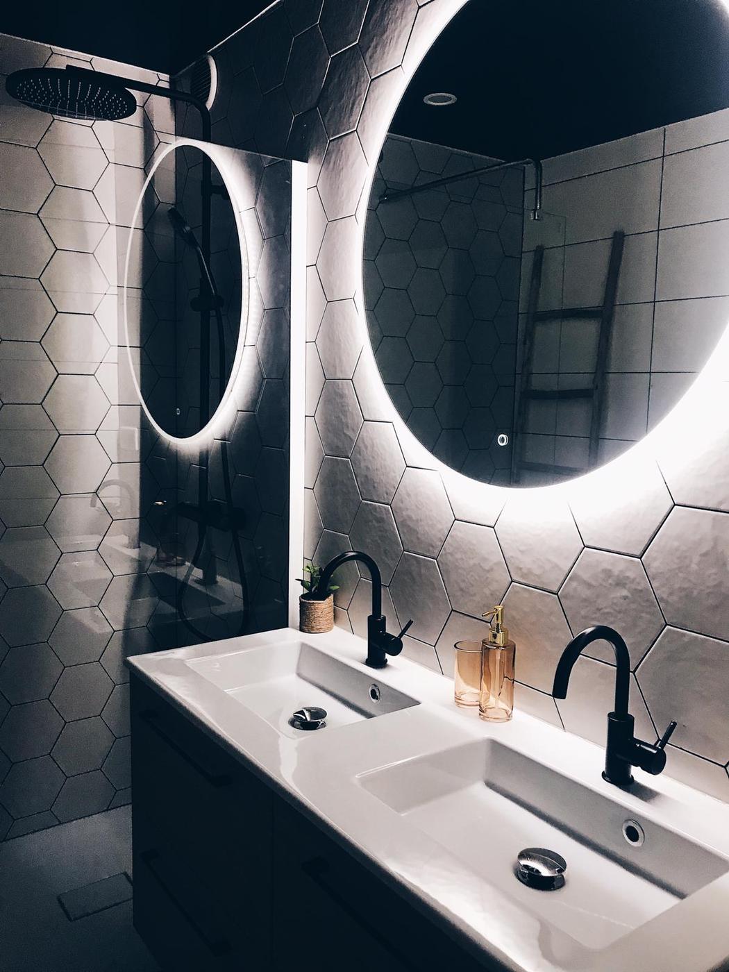 Carrelage en pierre blanc hexagonal 17.5x20 cm dans une salle de bain noire avec vasques modernes et miroir lumineux