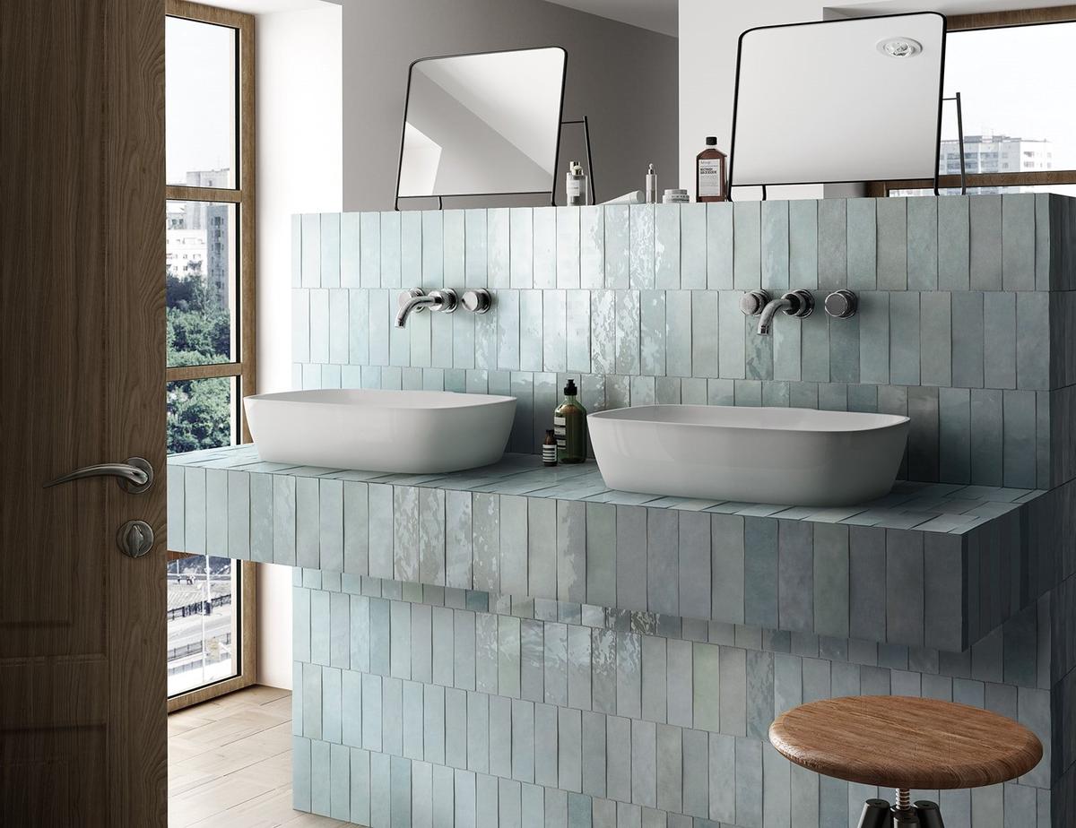 Carrelage Zellige bleu clair et varié sans motifs 6,5X20 sur un mur de salle de bain tons bois et blancs avec deux vasques ovales
