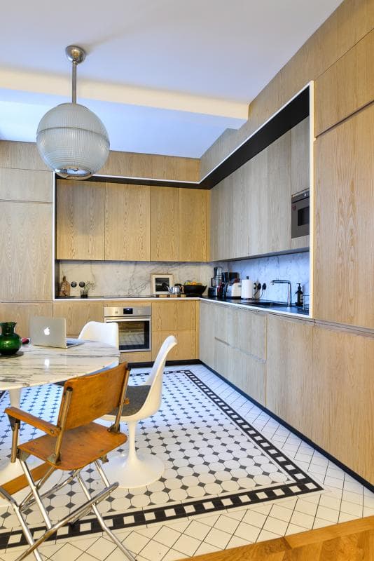 Carrelage uni blanc avec motifs géométriques noir dans une cuisine moderne bois clair et électroménager encastré