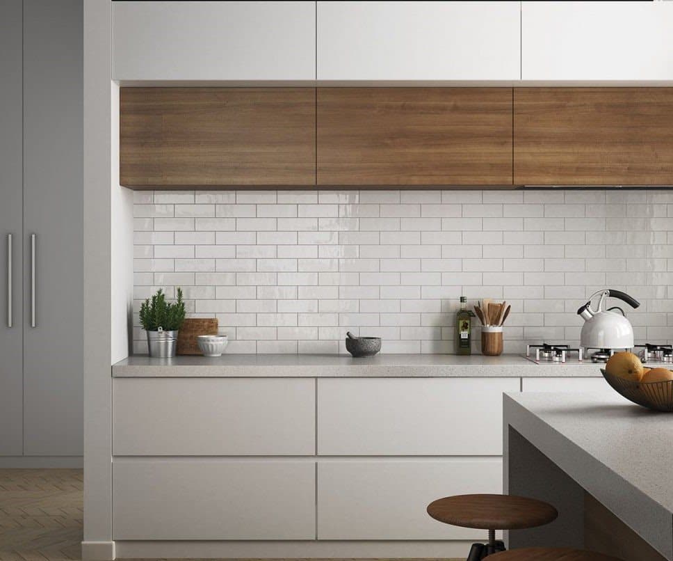 Carrelage uni blanc épuré dans une cuisine moderne sur des meubles gris avec plan de travail en granit, accessoires de cuisine et plantes