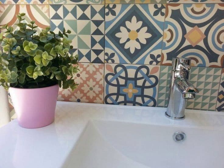Carreau de ciment multicouleur motifs géométriques et floraux 30x30 cm dans une salle de bain blanche avec plante verte et robinet chrome