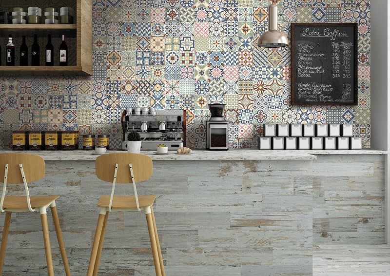 Carreaux de ciment multicouleur avec motifs géométriques et floraux 30x30 cm dans une cuisine blanche avec plancher effet bois clair et meubles modernes