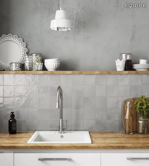carrelage Zellige gris sans motifs 10x10 cm dans une cuisine moderne gris clair avec plan de travail en bois et suspensions blanches