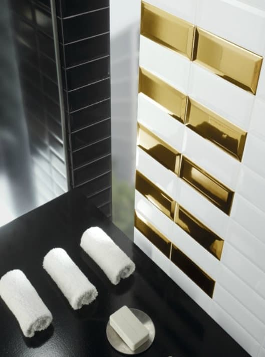 Carrelage uni blanc avec bandes dorées brillantes sur le mur dune salle de bain moderne avec serviettes blanches et savon