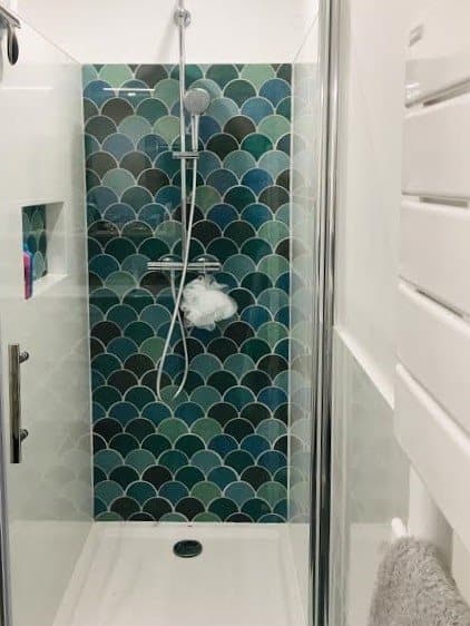 Carrelage uni vert écailles dans salle de bain moderne, blanc, douche vitrée, accessoires argentés