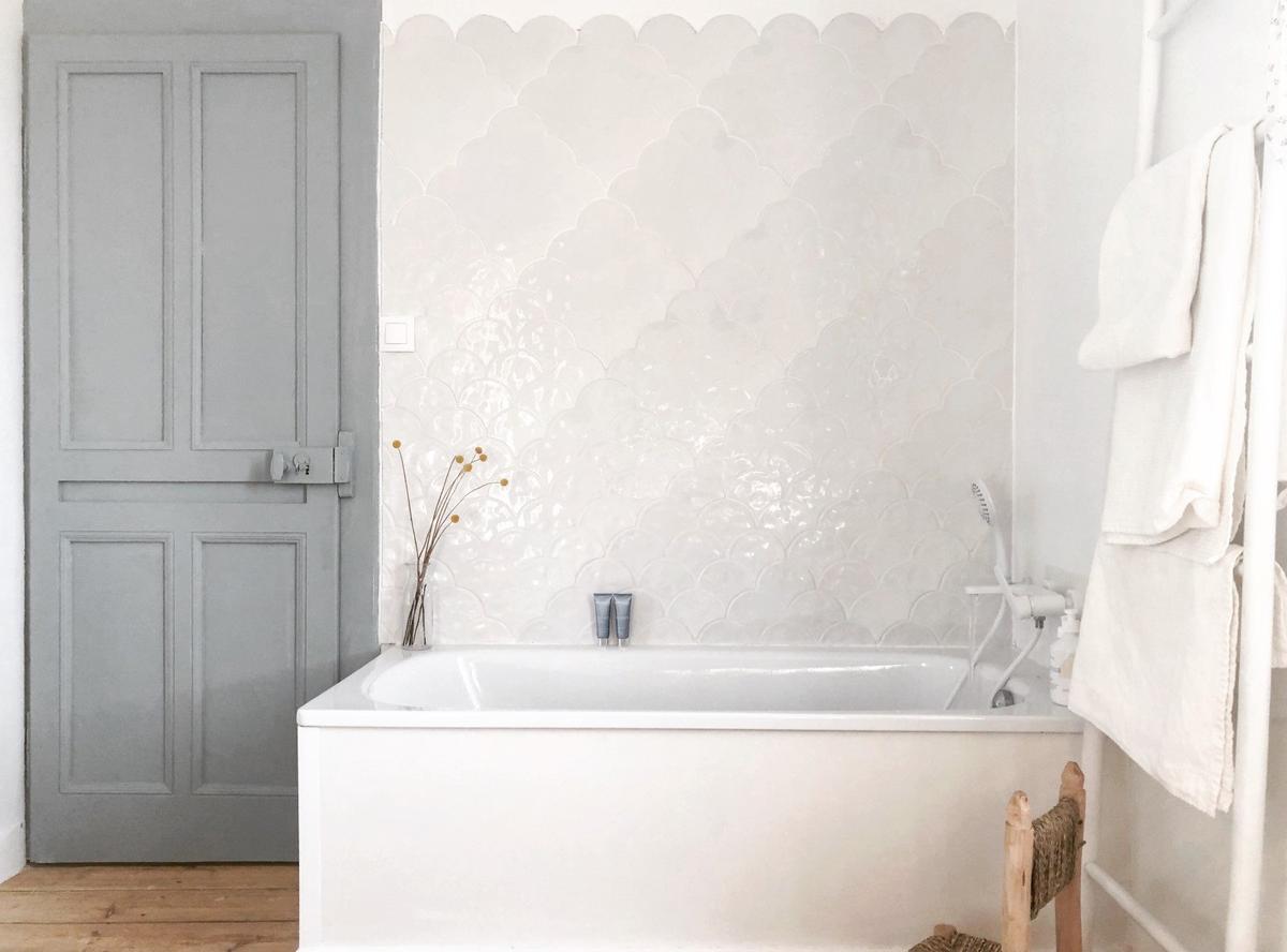 Carrelage blanc uni motifs subtils en relief 30x30 cm dans une salle de bain nuances de gris accessoires bois et blancs
