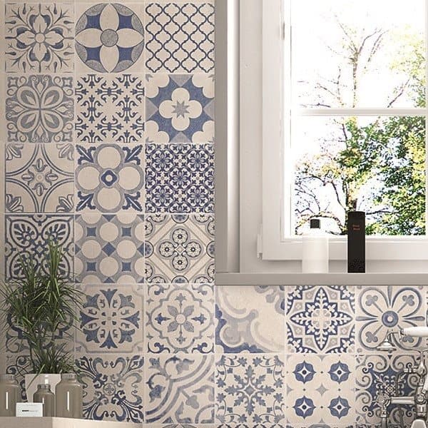 Carreaux de ciment bleus variés et motifs dans salle de bain blanche avec autres nuances de gris et objets de décoration