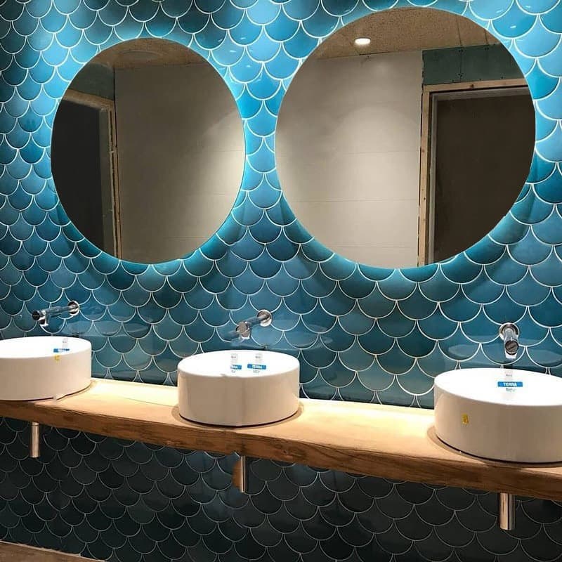 Carrelage uni bleu pétrole sans motifs 12,7X6,2 sur un mur de salle de bain beige avec vasques rondes et robinets en chrome