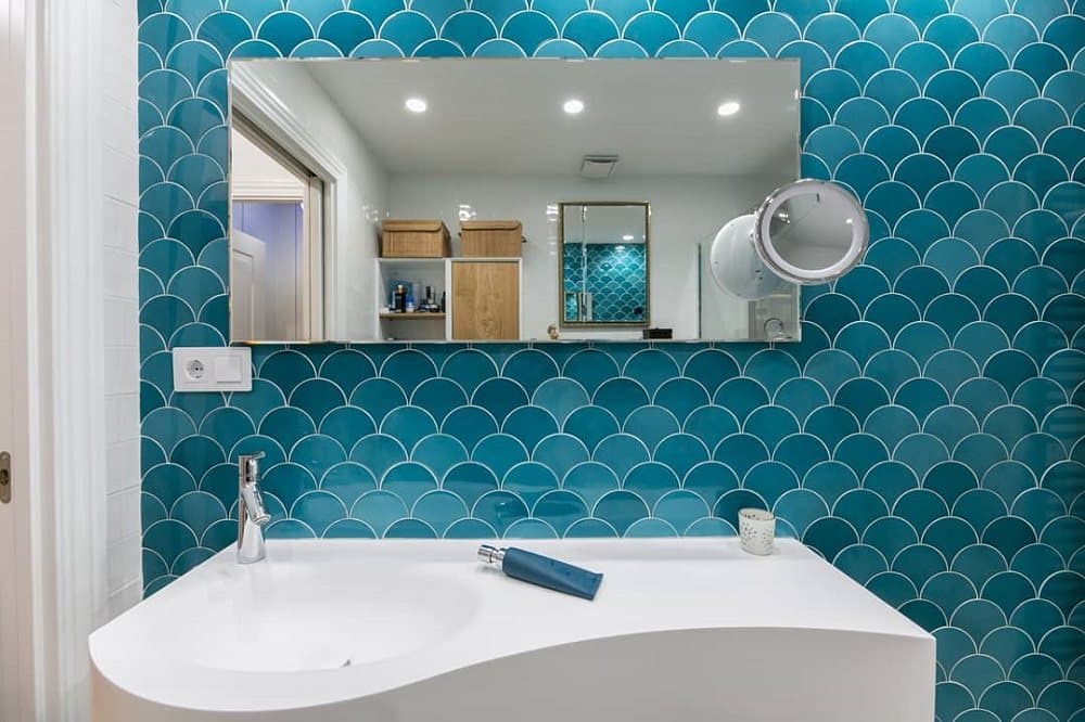Carrelage uni bleu turquoise 12,7X6,2 dans une salle de bain tons de bois clair et blanc avec miroir et lavabo