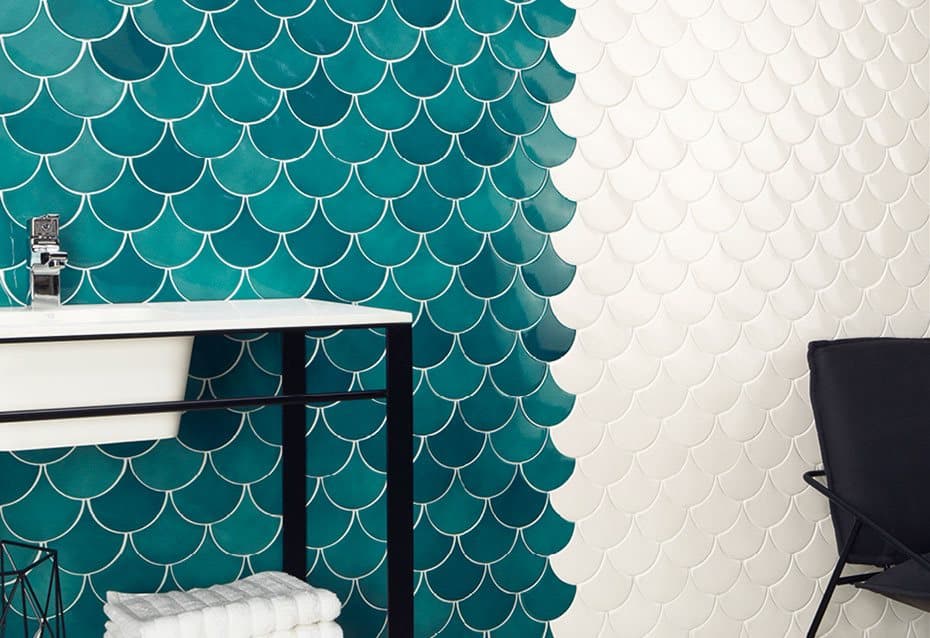 Carrelage uni blanc et turquoise avec motifs écailles sur mur de salle de bain, contrastant avec éléments noirs et blancs