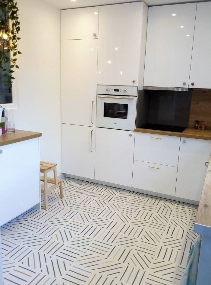 Carrelage effet tissu multicouleur motifs géométriques 20x20 cm dans une cuisine moderne avec meubles blancs et plan de travail en bois
