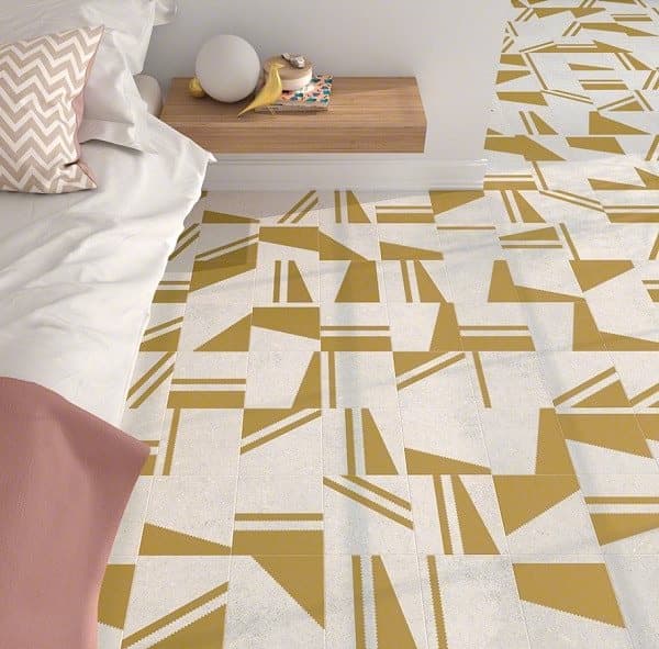 Carrelage effet pierre or avec motifs géométriques 20x20 cm sur sol dune chambre tons blancs et beige avec lit et coussins