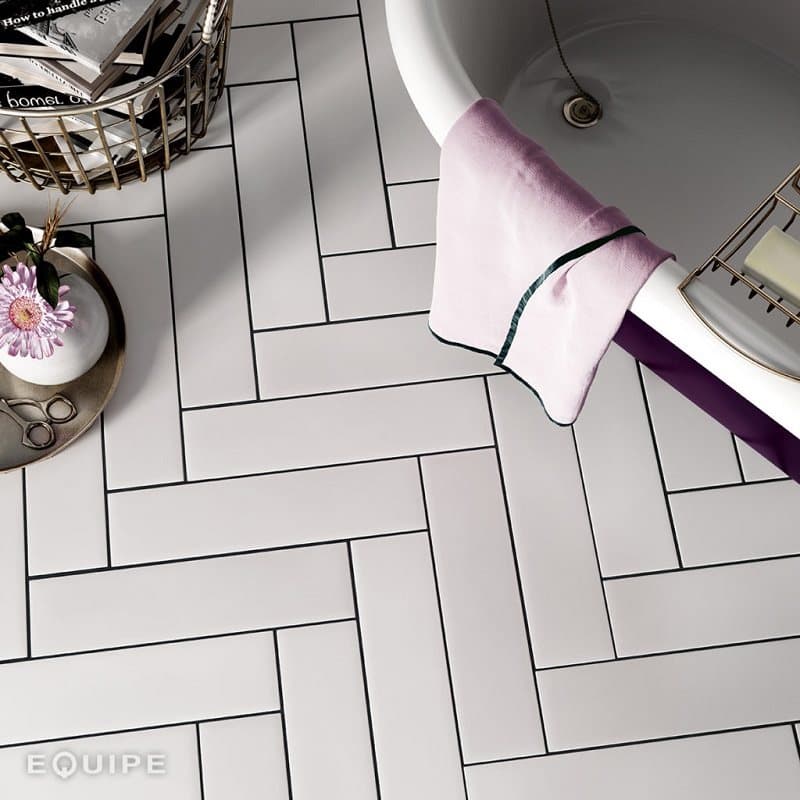 Carrelage uni blanc sur une salle de bain avec accessoires et linge violet