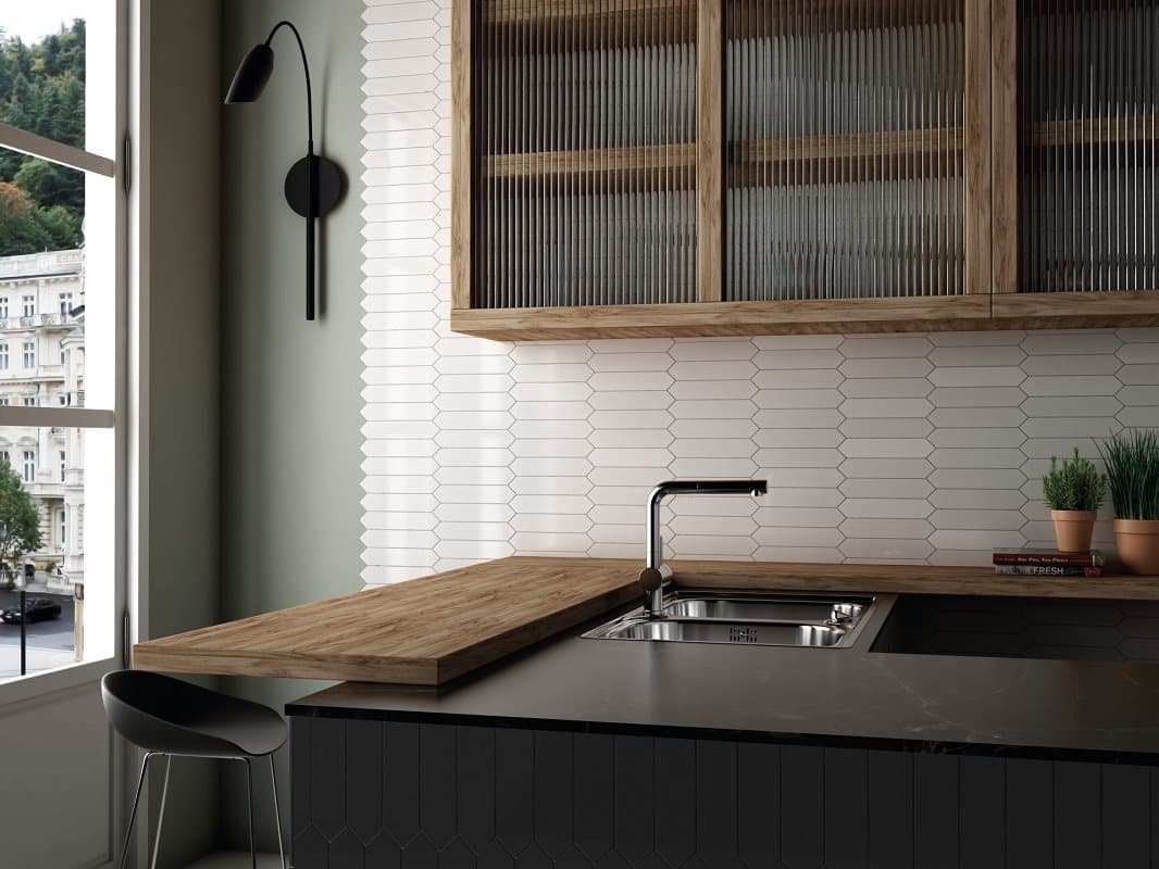 Carrelage uni blanc sur le mur de la cuisine avec armoires en bois et plan de travail gris, évier inox, dans un décor épuré et moderne