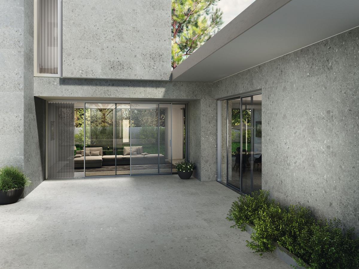 Carrelage effet pierre gris clair sans motifs 60x120 cm dans un salon moderne murs clairs mobilier taupe jardin visible