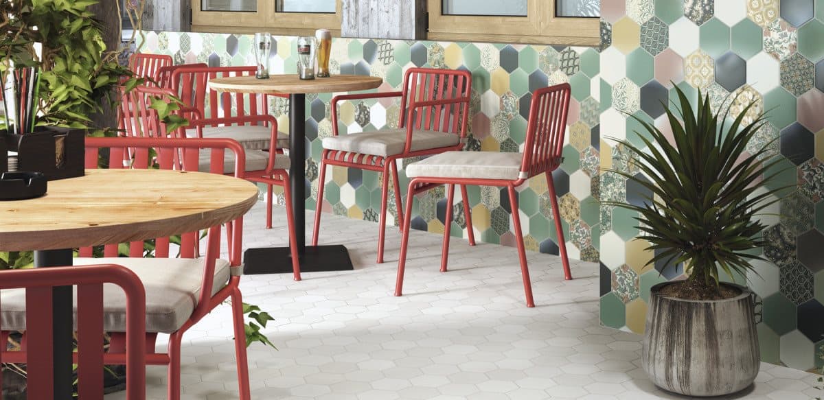 Carrelage uni blanc dans une salle à manger aux chaises rouges, mur multicolore, plantes vertes, éclairage naturel