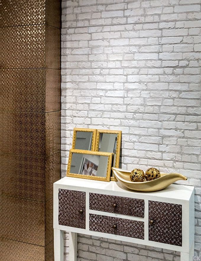 Carrelage blanc relief sans motifs sur un mur avec mobilier blanc et décoration dorée dans un espace intérieur moderne aux nuances marron et crème
