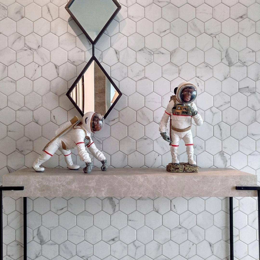 Carrelage blanc en relief hexagonal sur un mur avec figurines dastronautes sur console en intérieur moderne