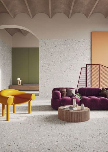Carrelage Terrazzo blanc avec nuances de gris 60x60 cm dans un salon moderne aux murs verts et accent orange, avec canapé pourpre et table jaune