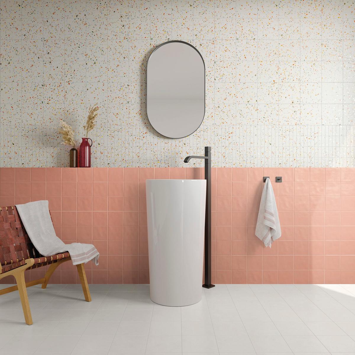 Carrelage Terrazzo blanc avec éclats multicolores 20x20 cm sur un mur de salle de bain tons roses et blancs, avec miroir ovale et lavabo moderne