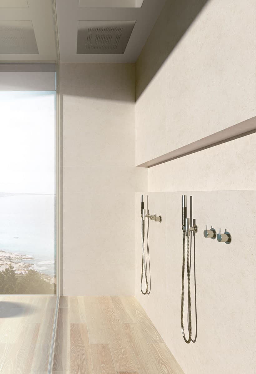 Carrelage effet métal blanc légère texture 60x60 cm dans une salle de bain épurée sur fond beige clair avec douche moderne et vue sur mer