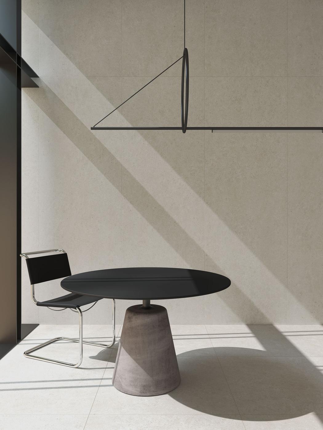 Carrelage aspect pierre gris sans motifs 60x60 cm dans une salle minimaliste beige avec une chaise noire et table design et luminaires modernes