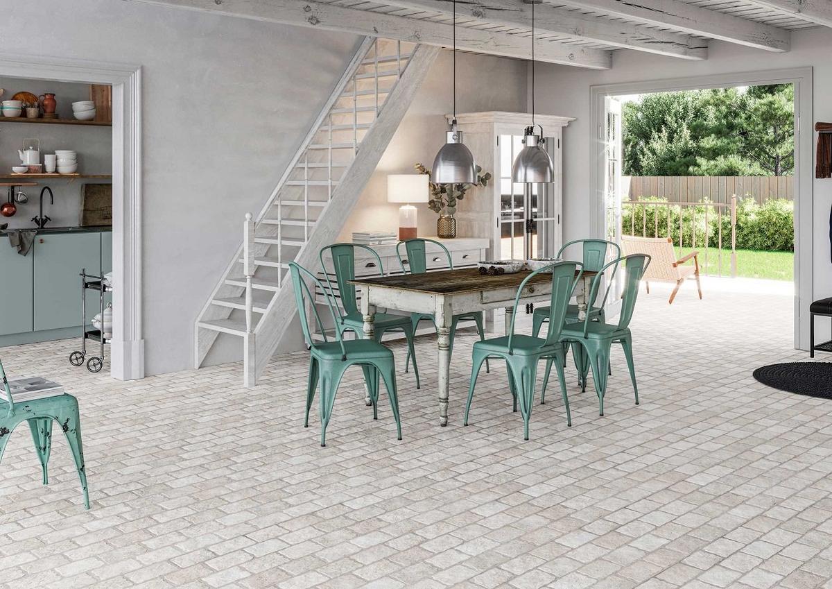 Carrelage effet pierre blanc dans un espace de vie ouvert sur lextérieur, nuances de gris, décor chaleureux avec table en bois, chaises vertes