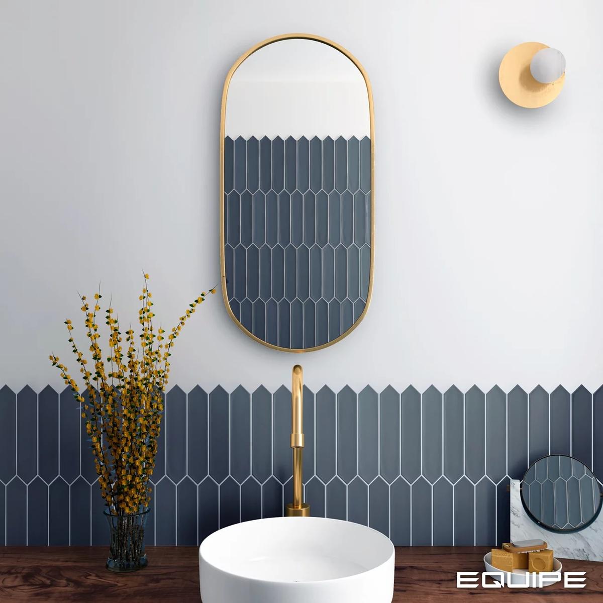 Carrelage uni bleu 5X25 dans une salle de bain blanc doré avec lavabo rond robinet doré miroir ovale et luminaire mural