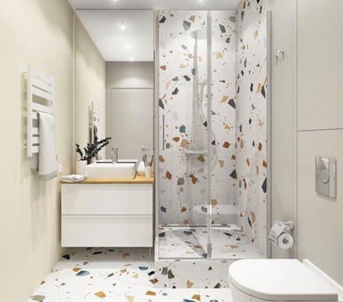 Carrelage Terrazzo aux nuances de terracotta avec éclats multicolores sur le mur et le sol dune salle de bain épurée blanche avec meubles assortis et miroir