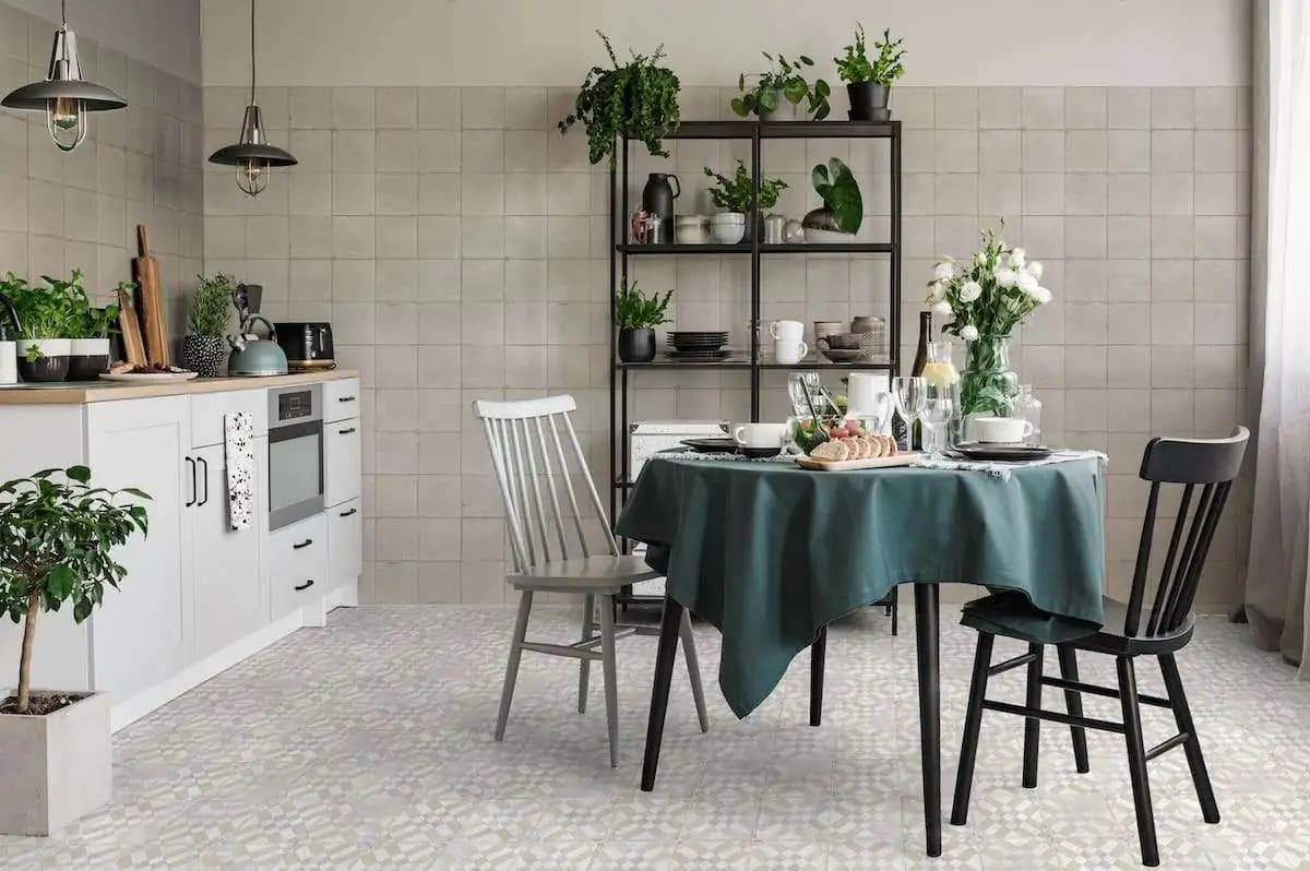 Carreau de ciment beige nuances de gris motifs géométriques 15x15 cm dans une cuisine moderne murs gris étagères en métal et plantes verts table dressée