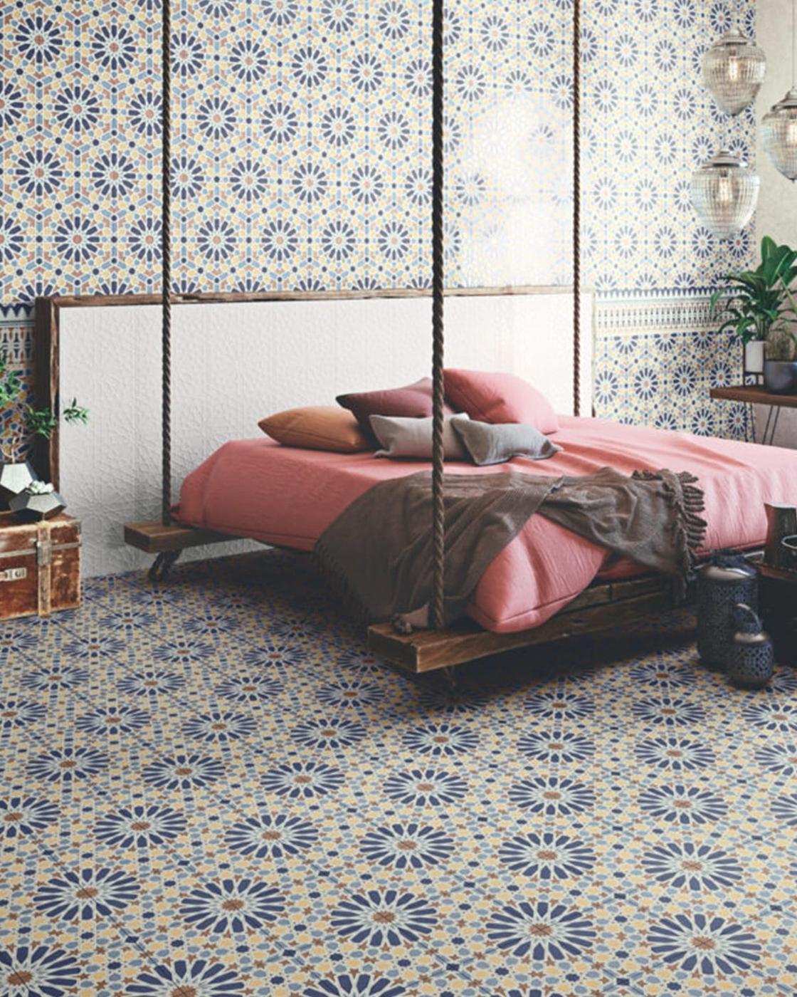 Carreau de ciment bleu à motifs détoiles dans une chambre aux murs bleus et lit terracotta, style vintage