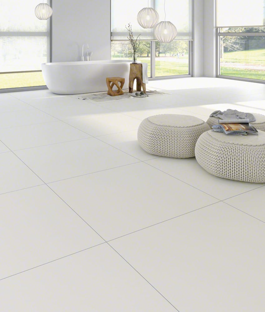 Carrelage uni blanc 80x80 cm dans une salle de bain épurée avec des nuances de gris et blanc, incluant baignoire îlot et poufs t