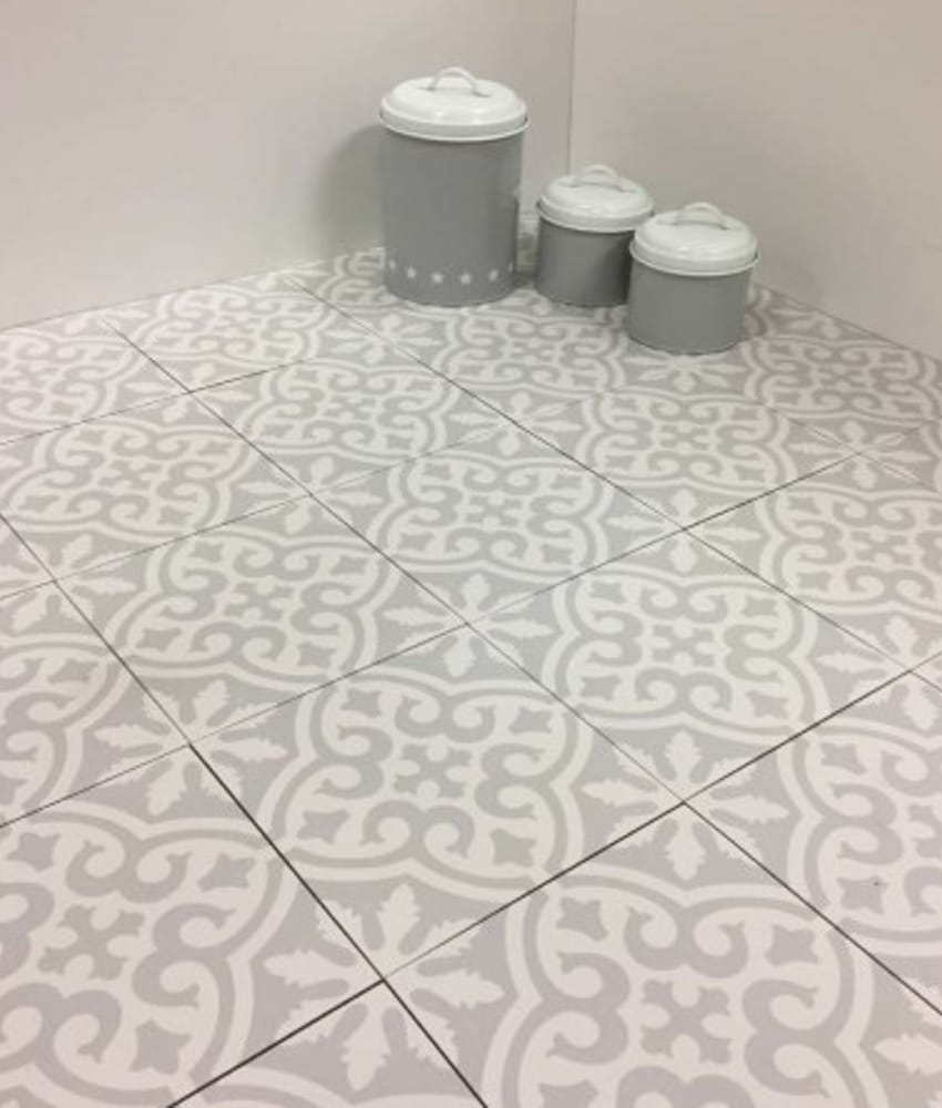 Carreau de ciment gris à motifs blancs 20x20 cm dans une pièce aux murs blancs avec trois pots décoratifs sur le sol
