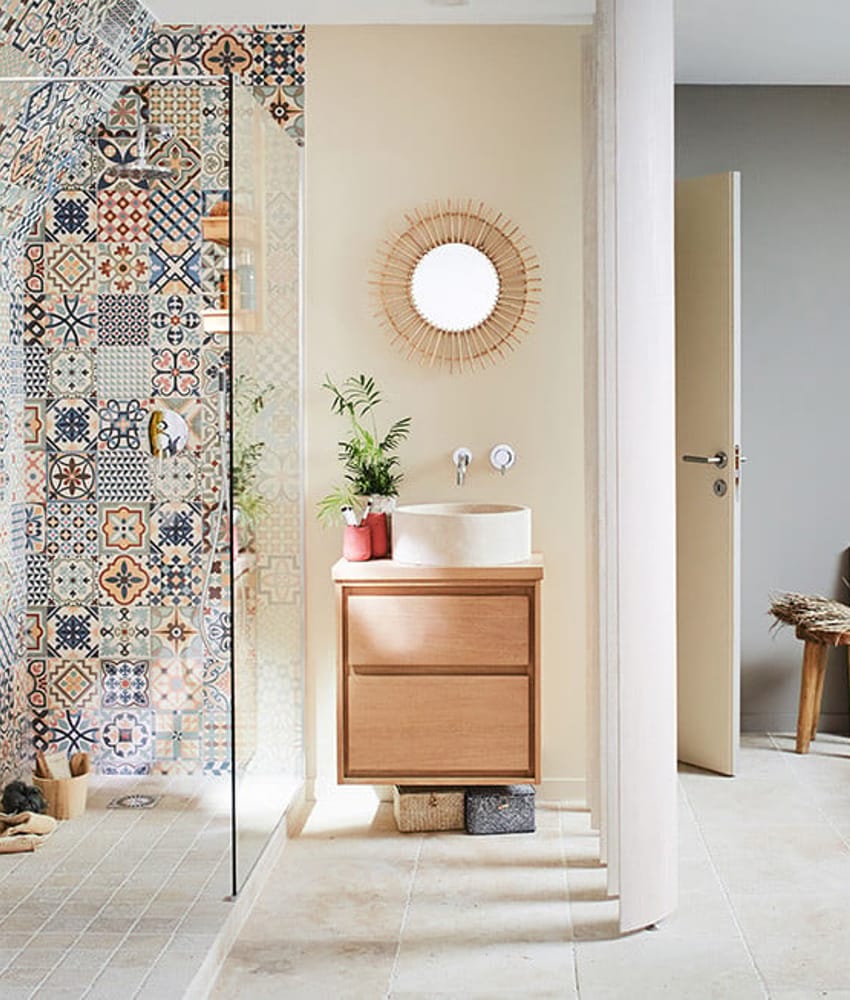 Carreau de ciment multicouleur motifs variés 30x30 cm dans une salle de bain beige avec meuble en bois clair et accents déco nat
