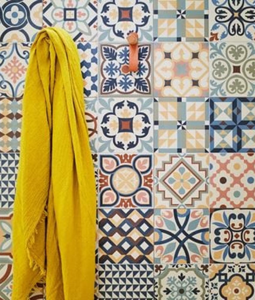 Carreau de ciment multicouleur motifs géométriques et floraux 30x30 cm sur une salle de bain murs blancs serviette jaune suspend