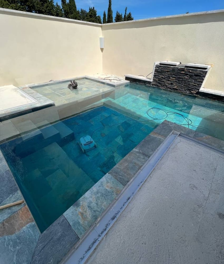 Carrelage pierre multicouleur 30x60 cm dans une piscine extérieure sur fond beige avec robot de nettoyage