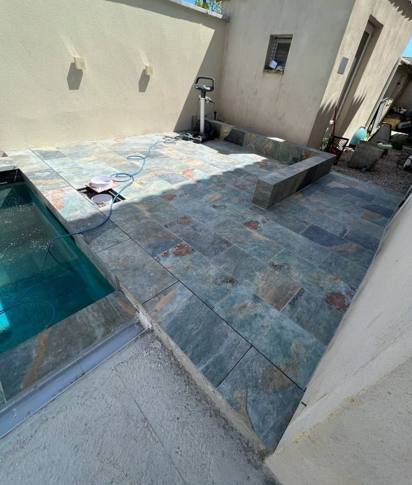 Carrelage pierre multicouleur avec nuances de bleu et de rouille 30x60 cm sur une terrasse extérieure beige avec piscine et équi