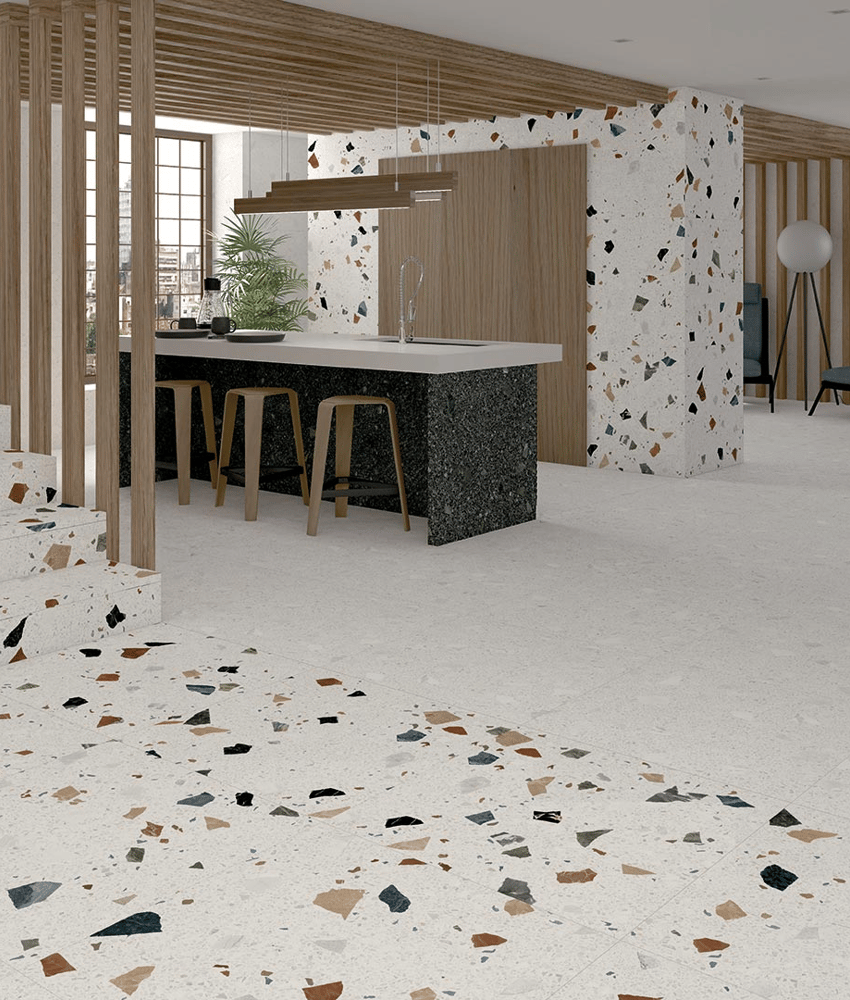 Carrelage Terrazzo blanc avec éclats multicolores 60x60 cm dans une cuisine moderne aux tons bois et gris avec îlot central