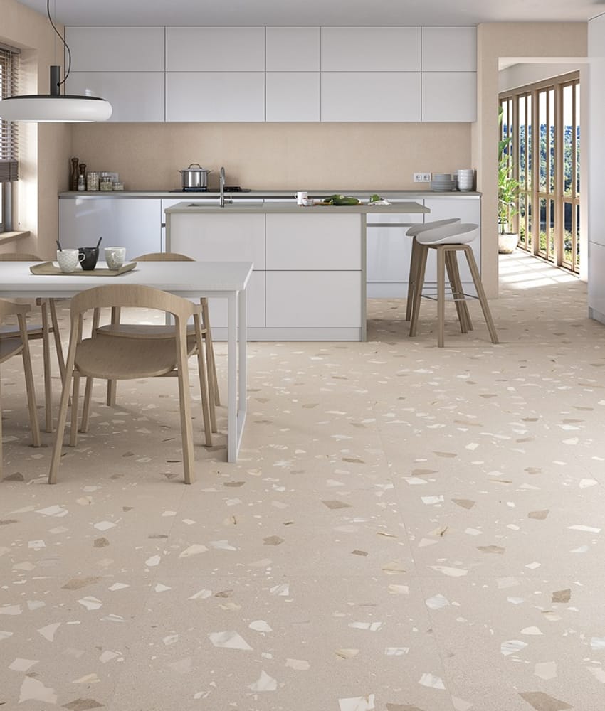 Carrelage Terrazzo beige avec éclats 80x80 cm dans une cuisine moderne blanche avec meubles et chaises en bois, donnant sur une 