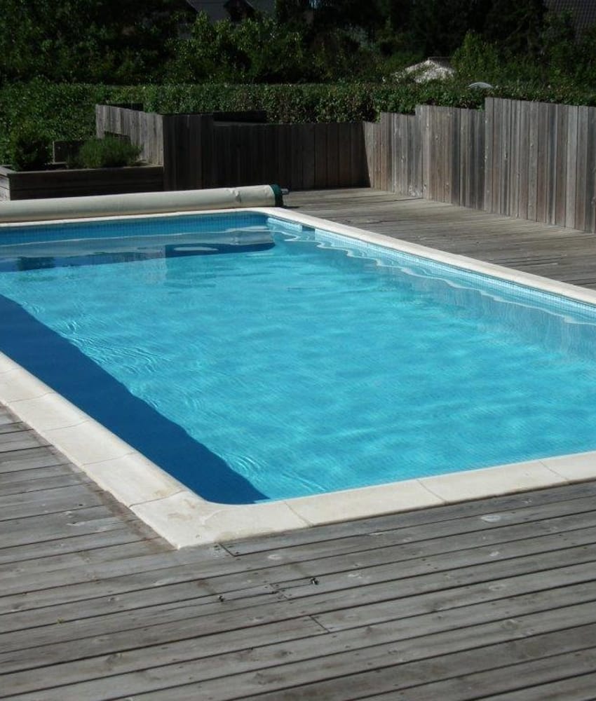 Carreau de ciment bleu clair et foncé sur une terrasse en bois autour dune piscine extérieure aux tons bleu ciel