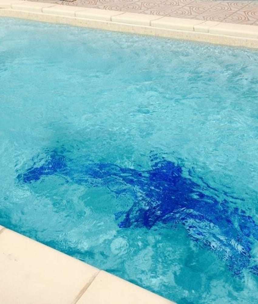Carrelage uni vert clair 30x30 cm sur le bord de piscine nuances de bleu eau transparente et chaises longues