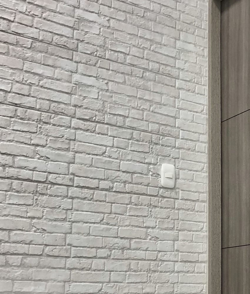 Carrelage blanc relief sans motifs sur un mur intérieur juxtaposant une porte en bois clair