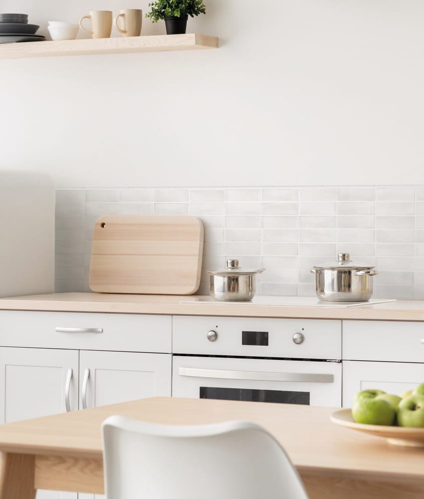 Carrelage Zellige blanc 5X15 dans une cuisine moderne aux murs blancs et meubles en bois clair, plans de travail et étagère en b