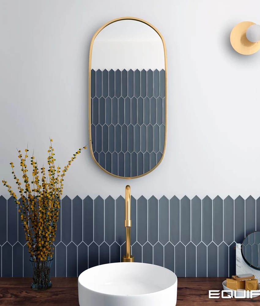 Carrelage uni bleu 5X25 dans une salle de bain blanc doré avec lavabo rond robinet doré miroir ovale et luminaire mural