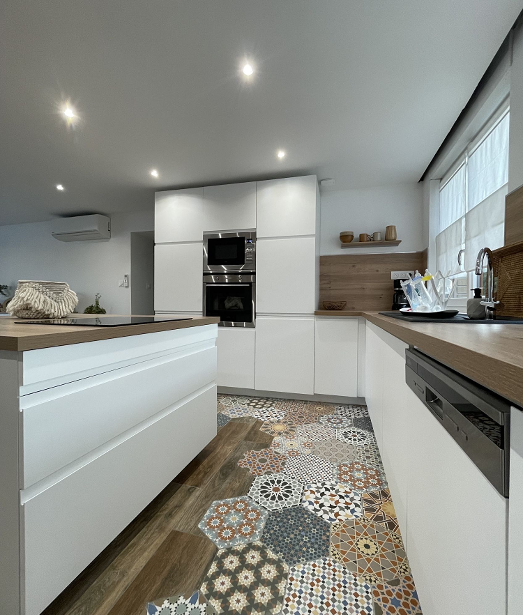 Carreau de ciment terracotta avec motifs variés 30x30 cm sur un sol de cuisine blanche avec bois et mobilier intégré