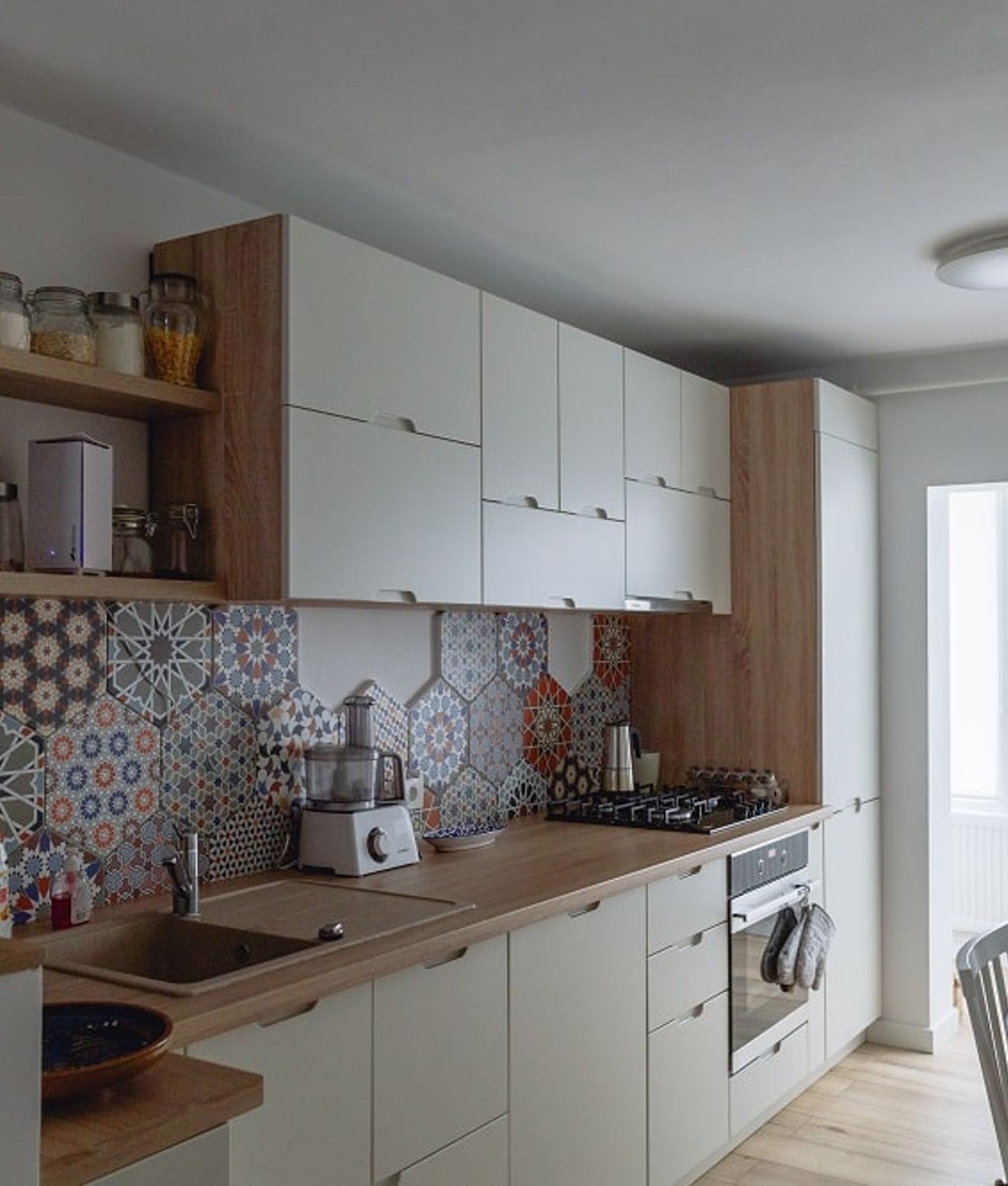 Carreau de ciment terracotta et multicolore motifs divers 30x30 cm dans une cuisine blanche et boisée avec étagères et appareils